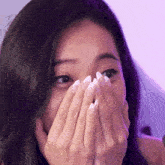 a woman covering her face with her hands and a purple background