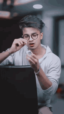 a young man wearing glasses looks at something in his hands