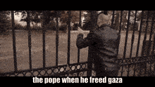 a man in a leather jacket is standing behind a fence with the words the pope when he freed gaza below him