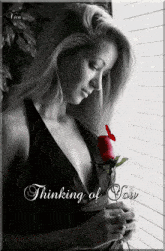a black and white photo of a woman holding a rose with the words " thinking of you " on the bottom