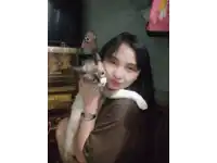 a woman wearing a watch holds a cat in her lap
