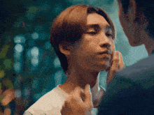 a man touching another man 's face with his hand