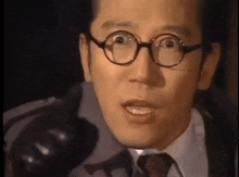 a close up of a man wearing glasses and a tie .
