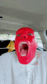 a man with a red mask on his face is screaming in a car