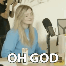 a woman is sitting at a table with a can of soda and a microphone and says `` oh god '' .
