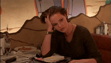 a woman is sitting at a table with her head resting on her hand