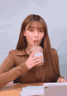 a woman is drinking from a plastic cup with a straw .