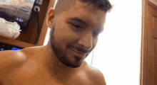 a shirtless man with a beard is smiling in front of a television that says 4:59 on it