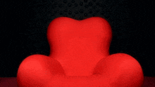 a person standing next to a large red chair with a black background