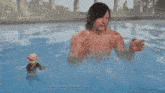 a man without a shirt is standing in a pool with a stuffed animal .