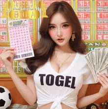 a woman wearing a t-shirt that says ' togel ' holds a lottery ticket and money