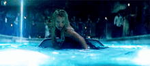 a woman is swimming in a pool with a crowd behind her .