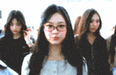 a girl wearing glasses is standing in a crowd of people