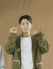 a young man wearing a green jacket and a white shirt