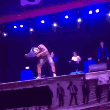 a shirtless man is dancing on a stage in front of a crowd of people