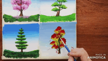 a person is painting four different trees on a canvas made by animatica