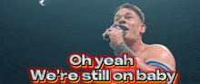 a man singing into a microphone with the words " oh yeah we 're still on baby " above him