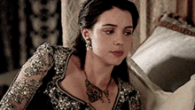 a woman in a black and gold dress is sitting on a bed .