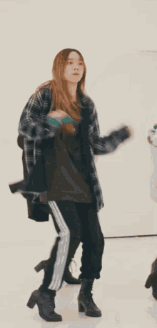 a woman in a plaid shirt is dancing with her hair in the air