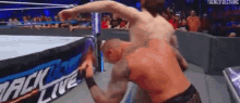 a man is wrestling another man in a wrestling ring while a crowd watches .