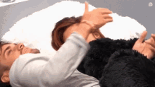 a man and a woman are laying on a bed with a blanket .