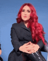 a woman with red hair is wearing a black jacket and black boots