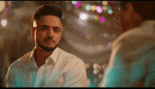 a man in a white shirt is looking at his reflection in a mirror