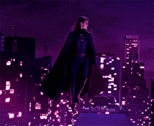 a woman in a cape is standing on top of a building in a city at night