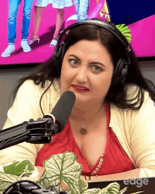 a woman wearing headphones is sitting in front of a microphone and the word edge is on the bottom right