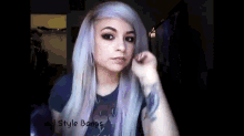 a woman with purple hair is wearing a t-shirt that says ' style bangs ' on it .