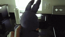 a purple stuffed bunny is sitting on a kitchen counter