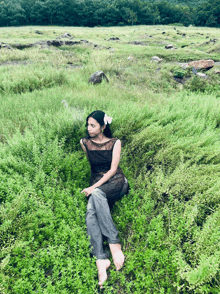 a woman with a flower in her hair is sitting in a field of tall grass