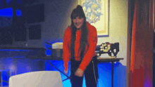 a woman in a red sweater is dancing in front of a table with a gun on it