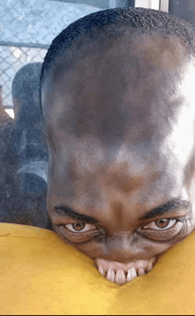 a close up of a person 's face with a yellow pillow in front of it