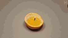 a person is peeling an orange with the letter h visible in the corner