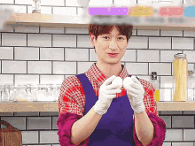 a man wearing an apron and gloves holds two eggs in his hands