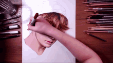 a person is drawing a woman 's face with a marker and pencils on the table