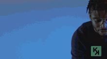 a man wearing glasses stands in front of a blue background that says chuva d.