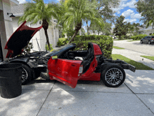 a red sports car with the hood up is sitting on the sidewalk