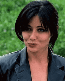 a close up of a woman wearing a black leather jacket and making a funny face .