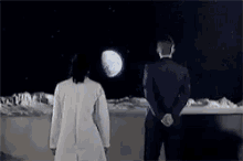 a man and a woman standing on the moon looking at the moon .
