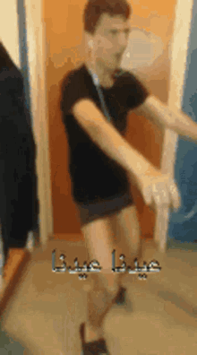 a man in a black shirt is dancing in front of a door with arabic writing on it