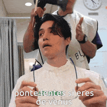 a man getting his hair blow dried by a man wearing a shirt that says bl on it