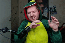 a man in a dinosaur costume stands in front of a microphone with the letter a on it
