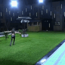 a woman is running on a lush green lawn in a dark room