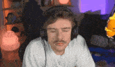 a man with a mustache wearing headphones is sitting in front of a microphone .
