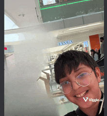 a young boy wearing glasses is smiling in front of a tanca sign