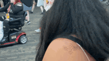 a woman with a tattoo on her shoulder has a scooter in the background