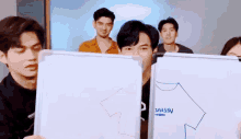 a group of young men are holding up whiteboards with drawings on them