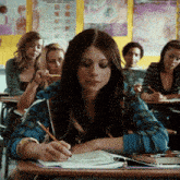 a woman sits at a desk in a classroom with other students